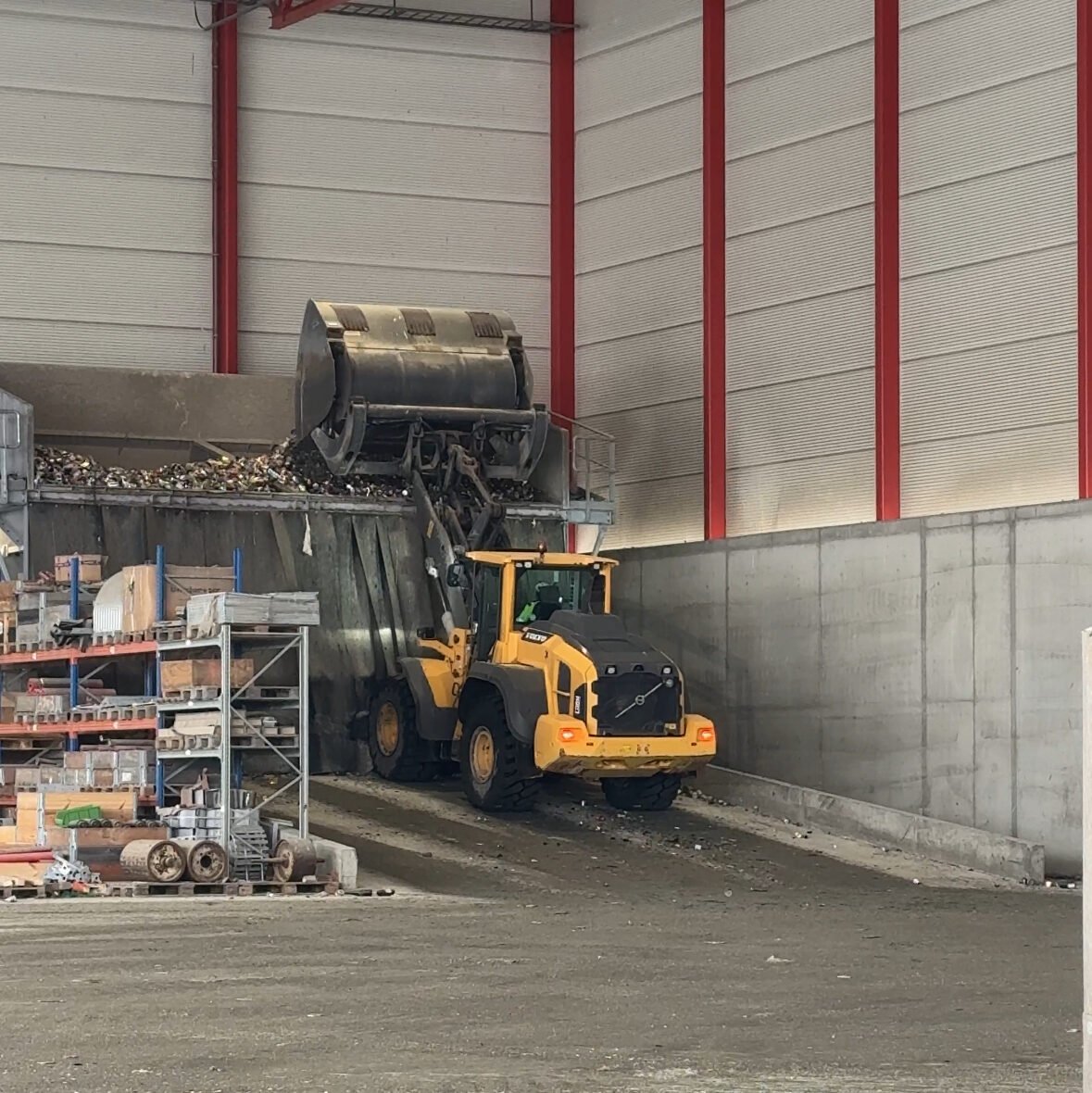 Traktor som frakter glass- og metallemballasje på båndet som går inn til sorteringsanlegget for gjenvinning av glass- og metallemballasje.