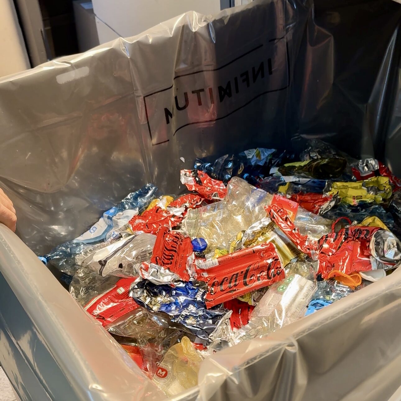 På baksiden av pantemaskinen i butikkene blir bokser og flasker klemt flate og og samles i en sekk.